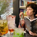 Anna Starobinets disfrutando de un cóctel mientras lee un libro.