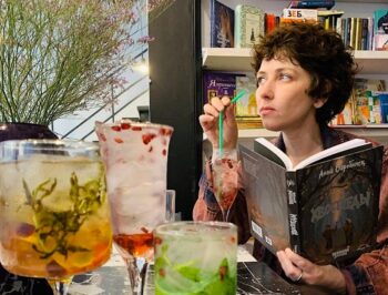 Anna Starobinets disfrutando de un cóctel mientras lee un libro.