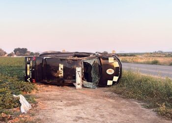 Coche de policía volcado en un campo junto a la carretera