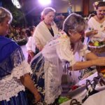 Mujeres en trajes tradicionales preparando ofrenda de frutas