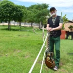 Antonio Baeza posando con guitarra en un parque verde