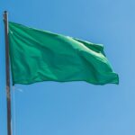 Bandera verde ondeando en la playa de Los Narejos bajo un cielo azul