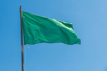 Bandera verde ondeando en la playa de Los Narejos bajo un cielo azul