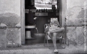 Persona leyendo una revista en la entrada de un bar en Torre Pacheco