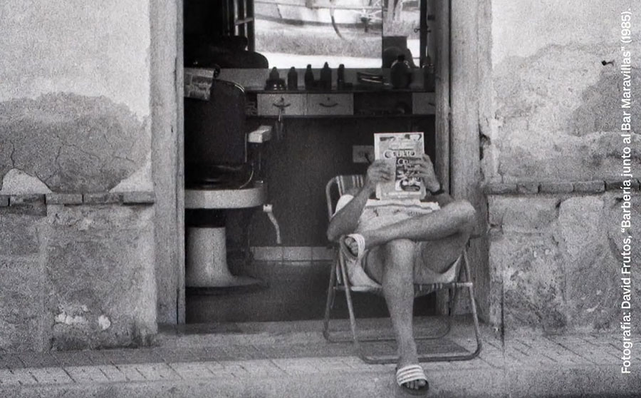 Persona leyendo una revista en la entrada de un bar en Torre Pacheco
