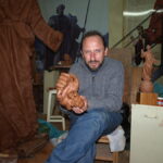 Juan José Quirós sosteniendo una escultura en su taller de trabajo.