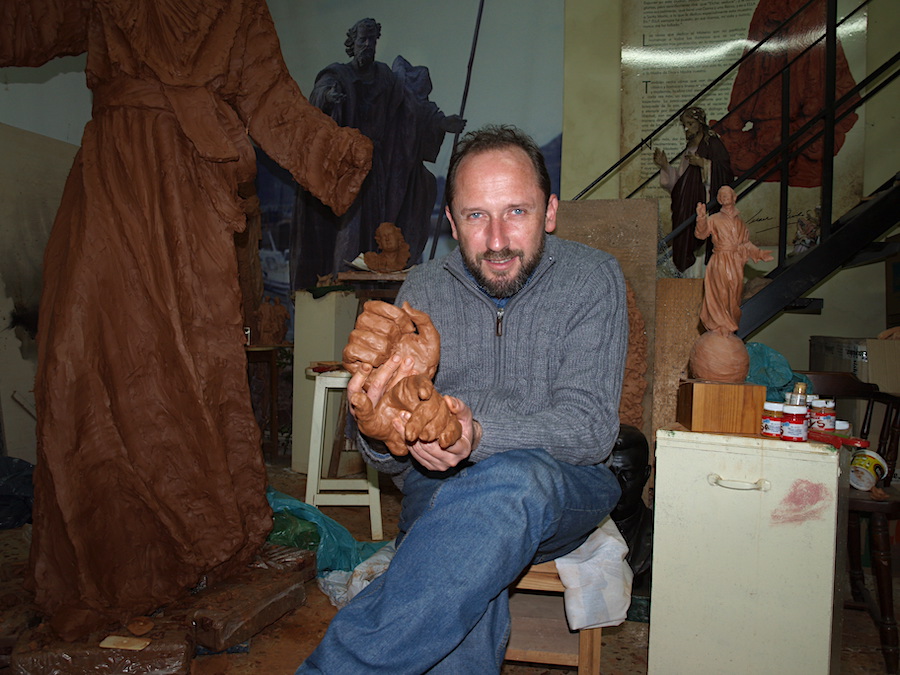 Juan José Quirós sosteniendo una escultura en su taller de trabajo.