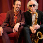 Lluís Coloma y un músico posando con un saxofón en un sofá