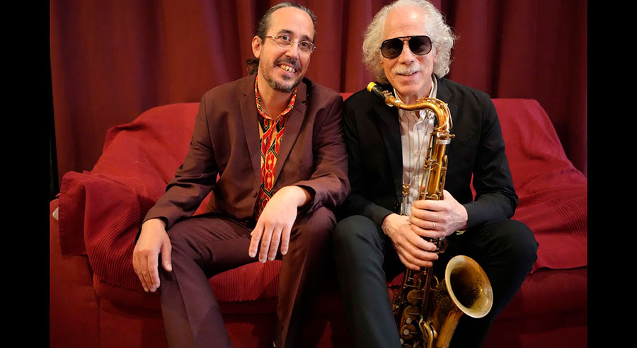 Lluís Coloma y un músico posando con un saxofón en un sofá