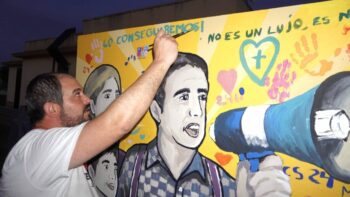 Hombre pintando un mural en apoyo a un centro de salud 24 horas