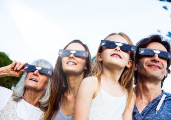 Familia usando gafas de eclipse en la playa