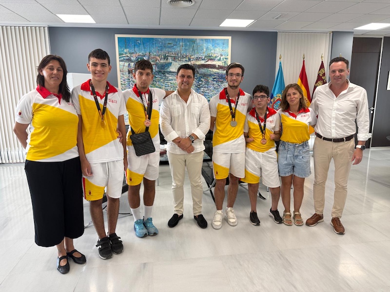 Grupo de jóvenes deportistas con medallas en recepción oficial